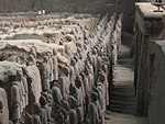 A large number of lined up human sculptures in a pit.