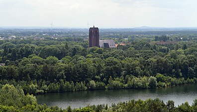 Zicht op Eisden-Tuinwijk met typische kerktoren en laanbomen, vanaf de Lange Terril in Terhills