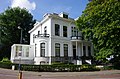 Statige neoclassicistische villa met onregelmatig verloop in fraaie tuin.