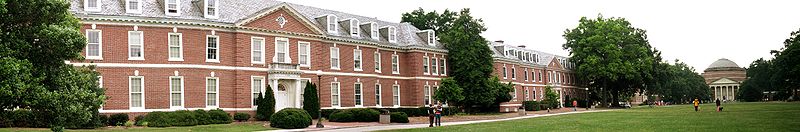 Panoramic photo of Georgian style buildings lining a grass lawn with a domed auditorium in the background