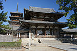 A two-storied wooden gate and a pagoda in the background.