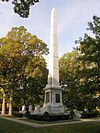 Weißer monumentaler Obelisk inmitten von Bäumen