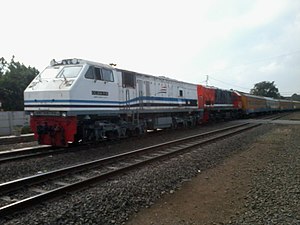 CC 204 11 15 menggandeng CC 201 83 41 dengan KA Rajabasa melintas langsung Stasiun Labuanratu.