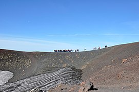 Touristen auf dem Weg rund um einen Krater, der bei einer Eruption des Ätna im Jahre 1892 entstand.