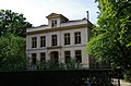 Statig neoclassicistische villa met onregelmatig verloop in fraaie tuin.