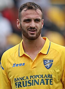 A standing man wearing a yellow sports shirt